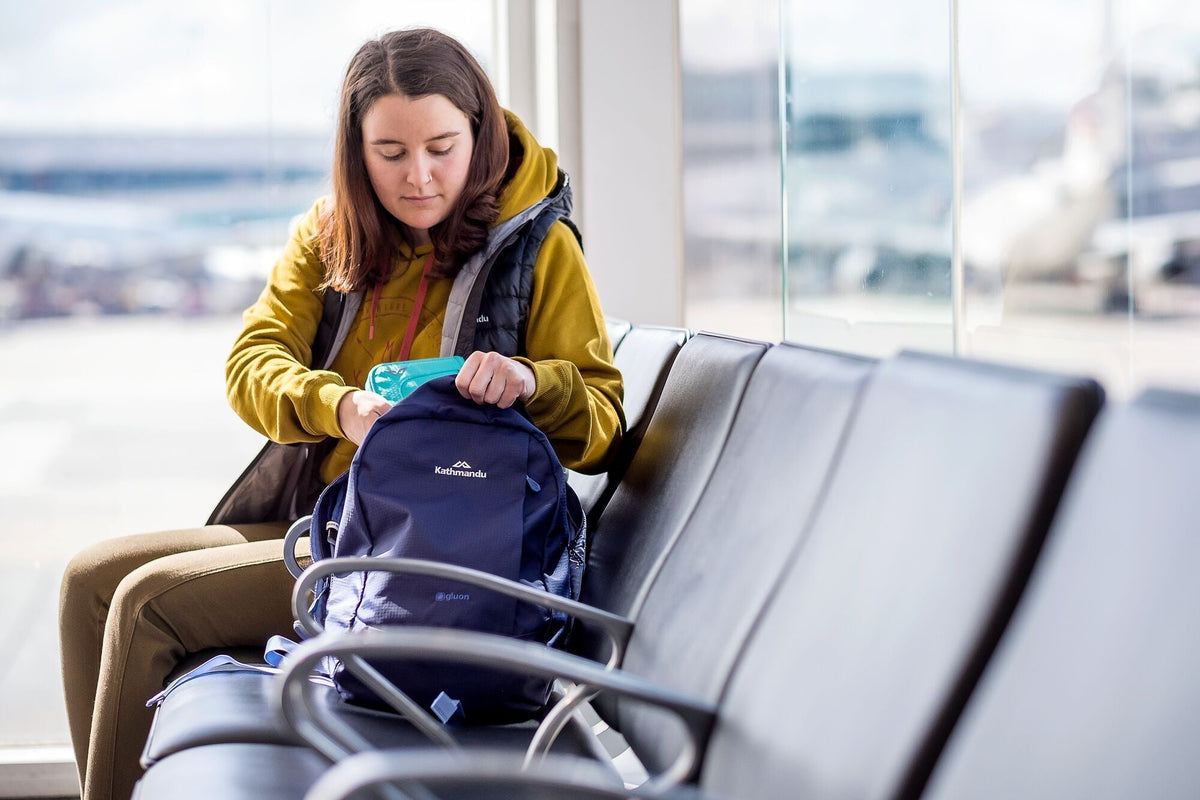 A lady looking through her carry on luggage at the airport ready to board her flight.
